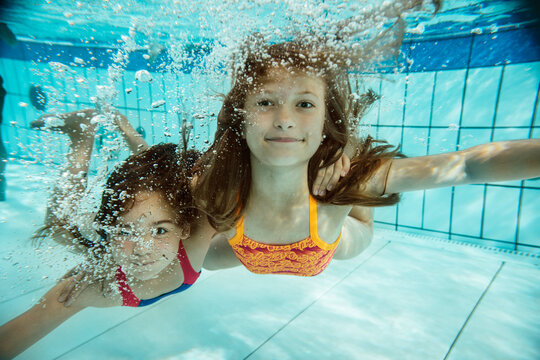 Portrait of two girls swimming under water in swimming pool