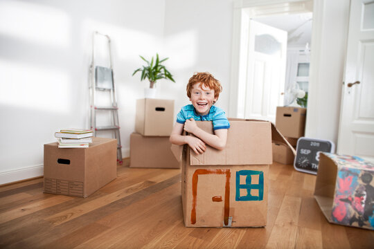 Happy boy looking out of a cardboard box in new apartment