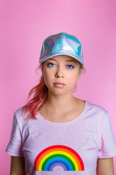 Portrait of stylish young woman wearing basecap in front of pink background