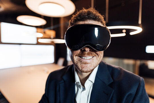 Smiling businessman wears a virtual reality headset in the office
