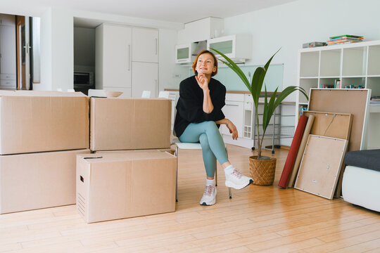 Woman sits beside cardboard boxes in her new modern apartment