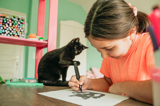 Girl drawing cat picture on paper at home