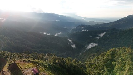 Aerial View of Misty Tropical Mountain Valley at Sunrise with Lush Rainforest Landscape © Alsy