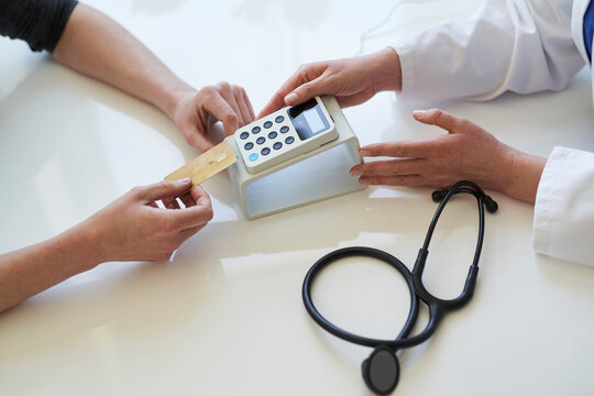 Doctor and patient with card and card reader at medical practice