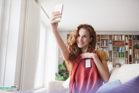 Smiling woman at home taking a selfie with new garment