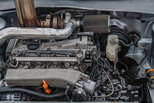 Vehicle engine bay showcasing boxer engine, air intake system, hoses, wires, metallic components, highlighting details in natural light under car hood