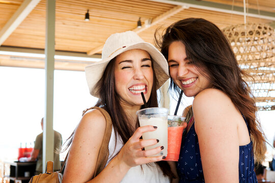 Two young woman drinking cocktails in beach bar