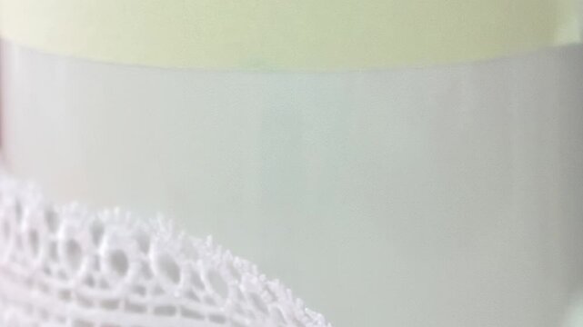 A close-up view reveals skilled hands meticulously placing delicate white lace onto a smooth, light-colored object.