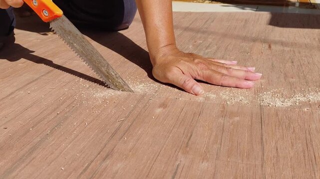 carpenter cutting wood board by using saw