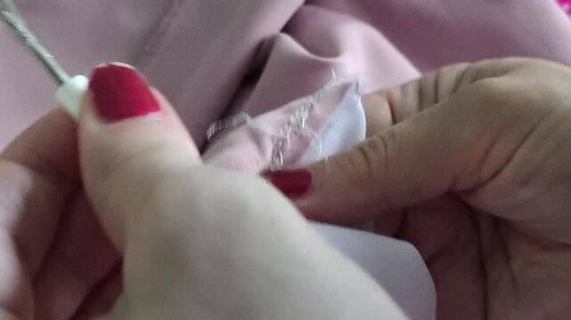 Professional seamstress removing stitches from fabric with seam ripper, garment alteration, dressmaking and textile production concept.