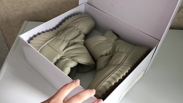 Woman packing shoes into storage box, organizing seasonal footwear at home, shoe storage, packing and home organization concept.
