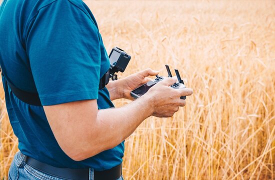 Precision agriculture operator with chest mount action camera holding drone remote controller
