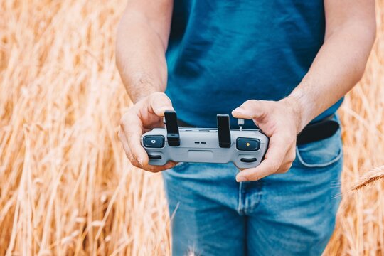 High tech farming concept with professional operator holding drone controller in a rye field