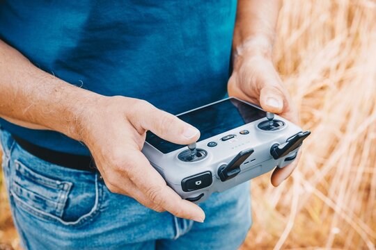 Farmer using drone remote controller for crop monitoring and field scanning in summertime