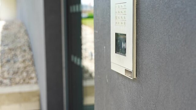 Person using contactless key fob on residential building access control system. Secure entry technology supports convenient and controlled property access