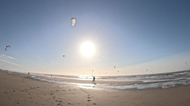 Scenic sunset footage of kitesurfers at Kijkduin Beach in the Netherlands with glowing skies and colorful kites over the sea