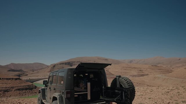 Off road 4x4 with open tailgate overlooking Barrage Toudgha reservoir in Morocco