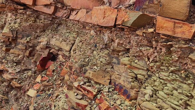 Tracking shot revealing layered sedimentary rock with colorful mineral staining weathered shale and sandstone formations
