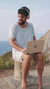 vertical Remote worker typing on laptop outdoors with scenic ocean view