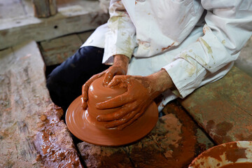 Craftsman Centering Clay on Pottery Wheel in Rustic Workshop