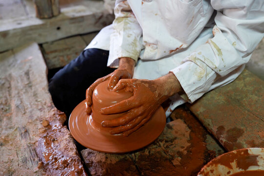 Craftsman Centering Clay on Pottery Wheel in Rustic Workshop