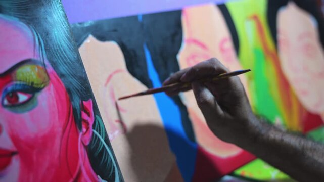 Close-up shows a finished colorful female movie face template on a rickshaw metal board while an artist's hand paints adjacent panels, archiving an endangered folk custom in Bangladesh.