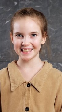 Pretty young girl with blue eyes looking directly at the camera. Her expression changes from serious to a joyful, wide smile, showcasing happiness, innocence, and positive energy