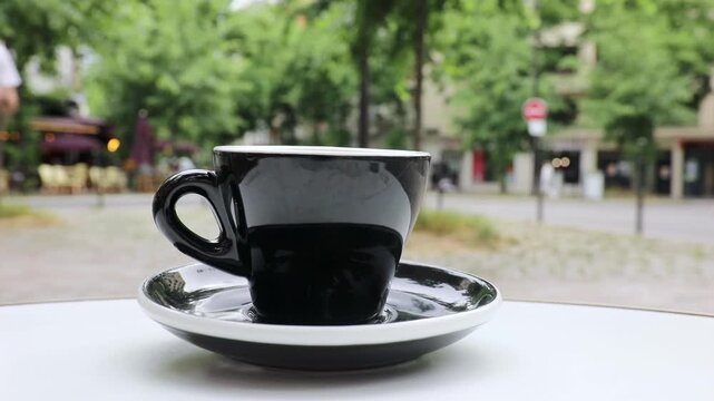 Cup of fresh hot coffee on the table of an outdoor cafe in Paris, France.