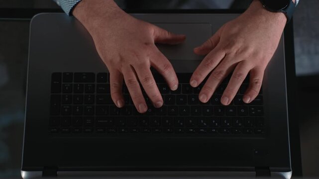 Top view of hands typing on laptop keyboard during computer work and completing online tasks of remote work