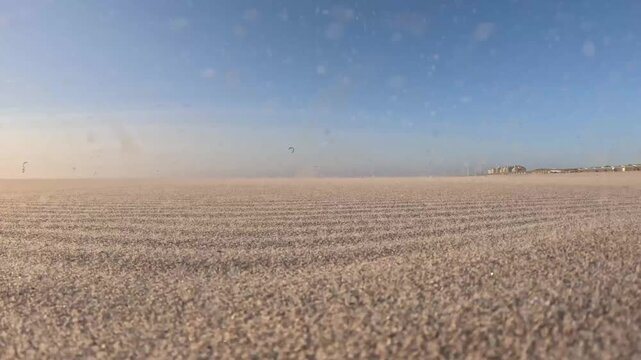 Powerful windstorm at Kijkduin Beach with kitesurfers riding the waves through blowing sand and sea spray