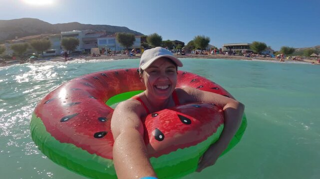 Woman floating on watermelon ring at sunny beach