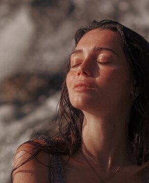 Close-up portrait serene young woman enjoying warm sunlight eyes closed outdoors