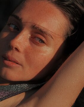Close-up portrait beautiful young woman with wet freckled skin looking away