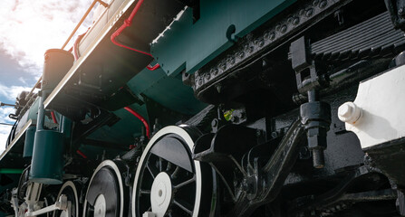 Low angle close up of historic steam locomotive wheels, suspension and mechanical engineering components showing industrial railway technology, transportation machinery and vintage train details. © Fahroni