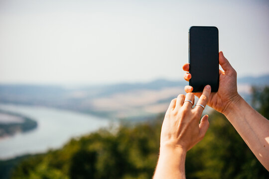 A person takes a mobile photo of a landscape while travelling.