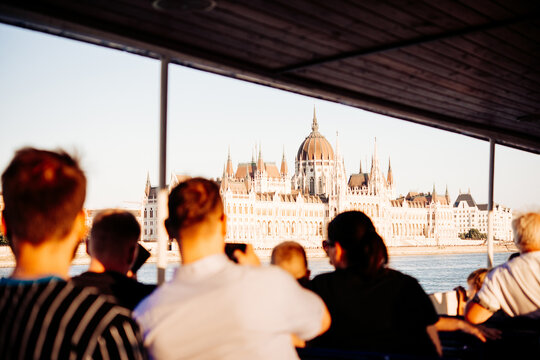 People on a river cruise enjoy the view of the Parliament building seen from the Danube river in the evening in Budapest, Hungary.