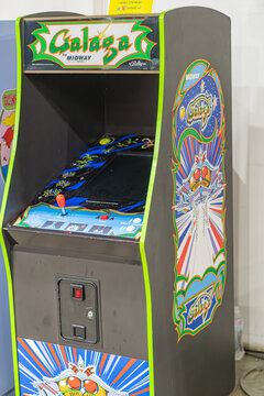 Vibrant blue and orange arcade machine Galaga, with a control panel featuring buttons and joysticks, showcasing an older model monitor displaying graphic content - Kyiv, Ukraine - June 7, 2025