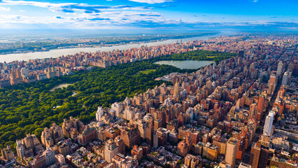 Naklejka premium Central Park reservoir and surrounding Manhattan residential buildings. High angle view of large lake, green park trees, urban blocks, river, horizon under clouds.