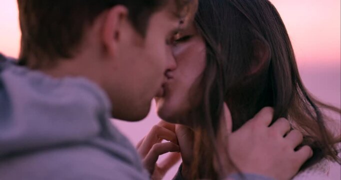 Love, nature and couple at sunset kiss for bonding, relax together and relationship by ocean. Dating, travel and man and woman with affection for romance on holiday, vacation and weekend outdoors