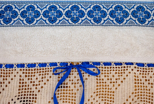 Cross-stitch pattern on a towel with lace trim and a blue bow.