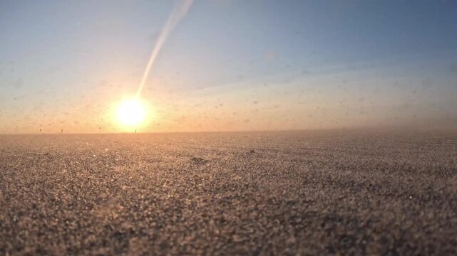 Epic North Sea sunset with blowing sand and colorful kitesurfers creating a dramatic coastal landscape