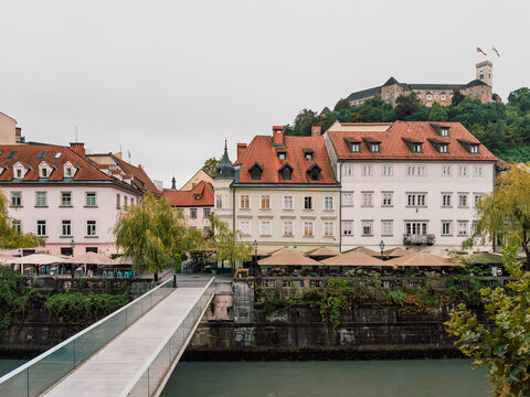 View of Ljubljana Castle rising above the historic old town and the Ljubljanica River in Slovenia with colorful buildings and a modern pedestrian bridge
