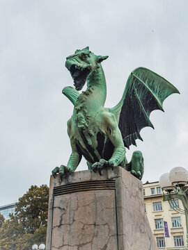 Famous dragon statue on Dragon Bridge in Ljubljana, Slovenia. Iconic bronze sculpture and symbol of the Slovenian capital against an overcast sky