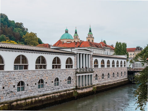 Historic Central Market building along the Ljubljanica River with Ljubljana Cathedral rising above the rooftops in the heart of Slovenia's capital