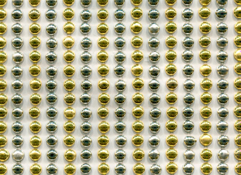 Metallic gold and silver circular studs forming a structured, repetitive grid pattern