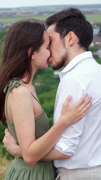 Passionate young man and woman sharing a romantic kiss while hugging tightly, expressing their deep love and affection for each other during an intimate date in a beautiful natural setting