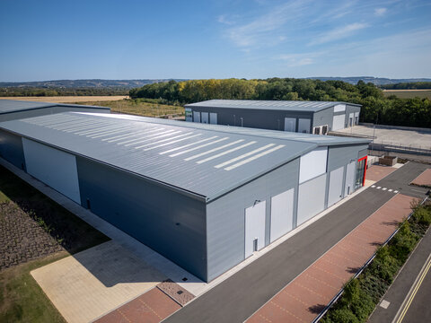 Aerial View of Modern Industrial Warehouse Complex in Green Countryside at Sunset &ndash; Commercial Buildings in Rural Setting