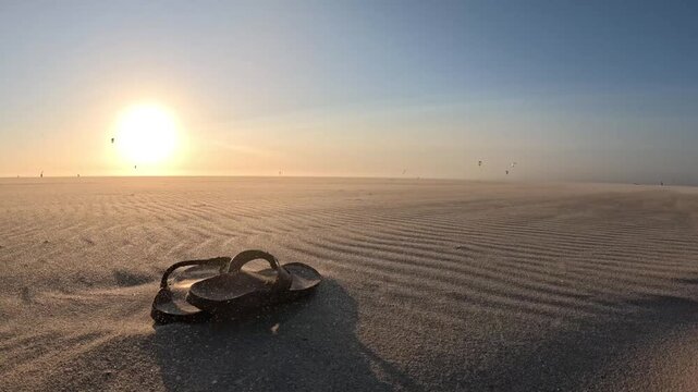 Cinematic Dutch beach sunset with flip-flops, blowing sand and colorful kites over the North Sea