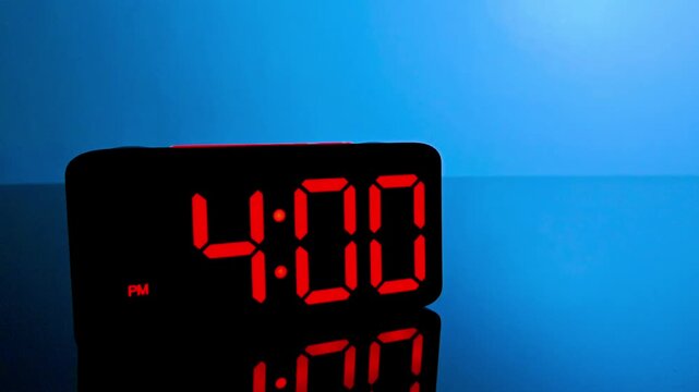 Digital alarm clock changing from 3:59 pm to 4:00 pm with red led display