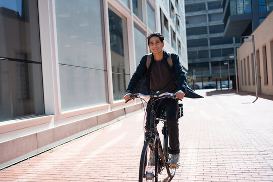 Young hispanic man riding bicycle in the city, commuting going to University campus or work